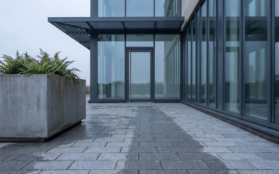 A glazed commercial entrance with grey block paving in front of it