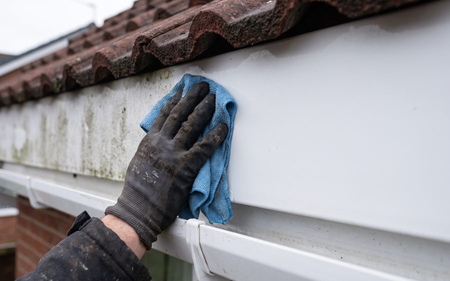 A white uPVC fascia board half cleaned, still grey green on the left