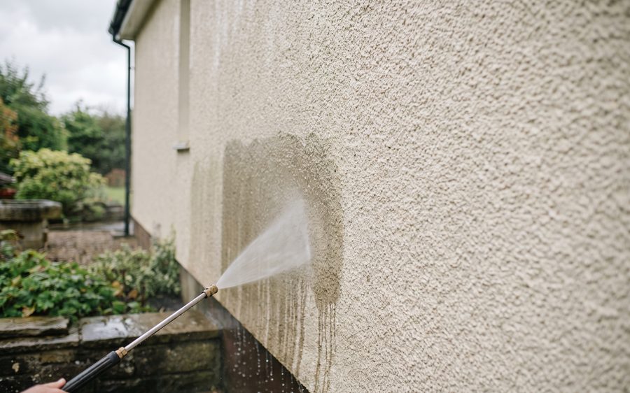 A low pressure fan of liquid being applied to a cream rendered wall